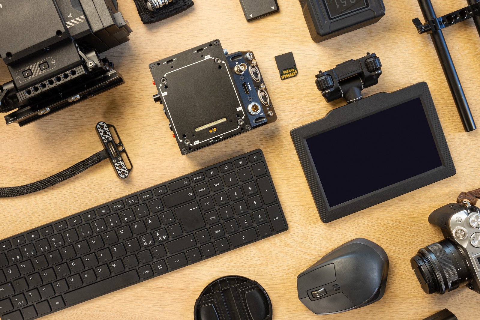 Flat lay of filming equipment with keyboard and mouse. Overhead view of video camera with computer parts on table. Directly above shot of various accessories arranged on surface.